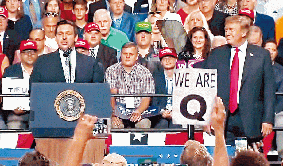 ■特朗普（右）周二晚佛州出席集會中，「Q」的追隨者高舉「我們是Q」標語，令該陰謀論社群打入主流視線。■「QAnon」成員身穿「Q」字T恤。■「WWG1WGA」（箭嘴示）是「Q」格言「Where we go one, we go all」。　