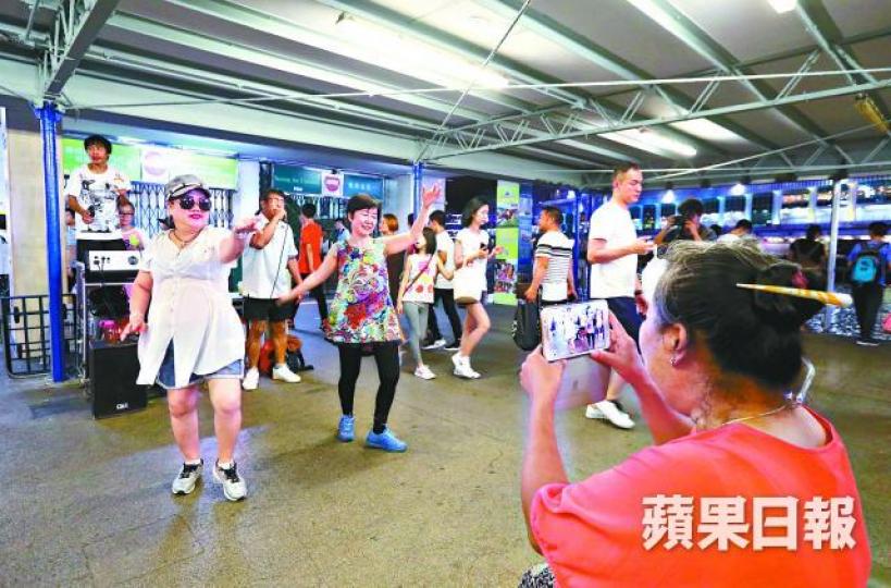 ■菜街大媽移師尖沙嘴天星碼頭載歌載舞。李家皓攝■「旺角阿Lam」被康文署職員阻撓後，轉用木結他演奏。
