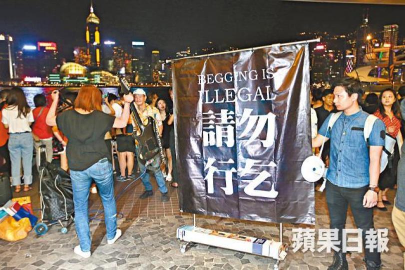 ■學獨聯陳家駒(右)昨晚在尖沙嘴向表演者展示「請勿行乞」海報。黎樹雄攝 ■學獨聯陳家駒(右)昨晚在尖沙嘴向表演者展示「請勿行乞」海報。黎樹雄攝