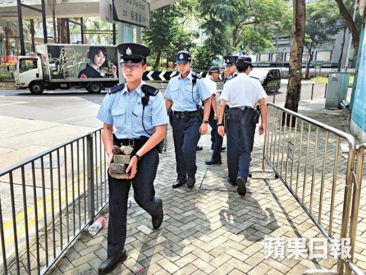警員昨到案發現場視察,撿走凸起的地磚。 警員昨到案發現場視察,撿走凸起的地磚。
