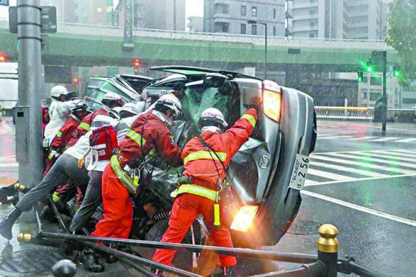 救援人員在大阪市內將被強風吹翻的車扶正。 救援人員在大阪市內將被強風吹翻的車扶正。