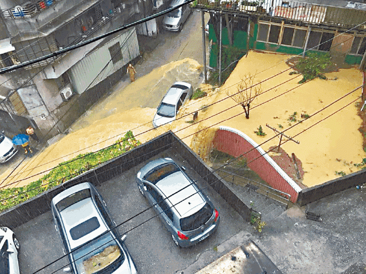 基隆復興路水淹及膝，許多車輛被浸。台北等地暴雨，途人狼狽。台灣《蘋果日報》