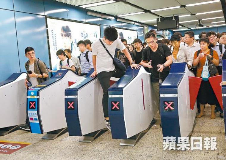 有趕乘港鐵的乘客跨過閘機。陳善南攝 有趕乘港鐵的乘客跨過閘機。陳善南攝