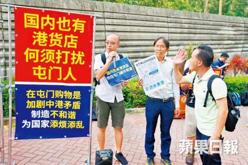 譚凱邦(中)等人在巴士站擺放簡體字標語,勸內地客留在內地消費。多名警員在場維持秩序,更「開路」協助內地客上巴士。黎樹雄攝 譚凱邦(中)等人在巴士站擺放簡體字標語,勸內地客留在內地消費。多名警員在場維持秩序,更「開路」協助內地客上巴士。黎樹雄攝