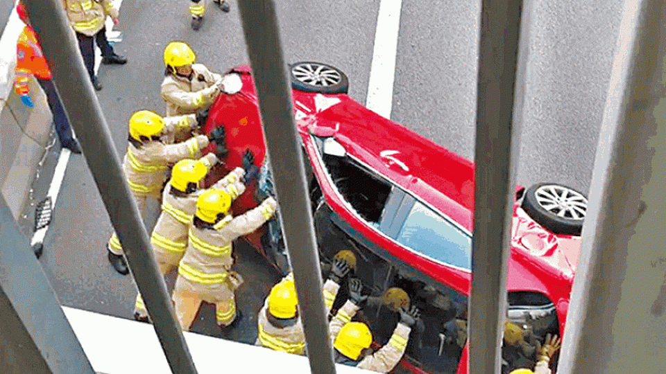 多名消防員合力將翻側私家車推正。讀者提供圖片 多名消防員合力將翻側私家車推正。讀者提供圖片