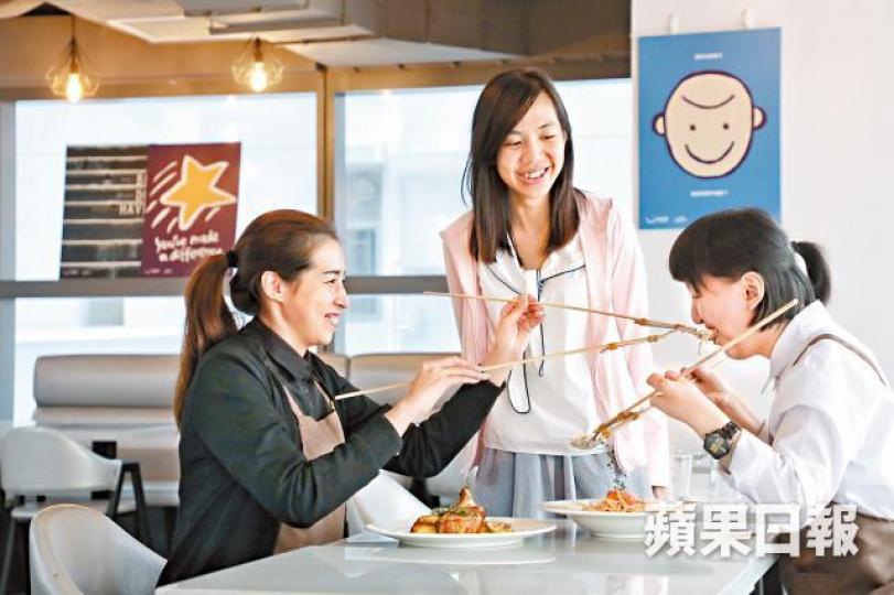 鄧家怡(中)與餐廳員工打成一片,二人正在示範食「天堂餐」,以增長的餐具互相餵食。社企餐廳走中高檔路線,希望為聽障和殘障人士提供就業機會,同時提供優質食物。籽樂廚房設開放式廚房,食客能看見師傅做菜,大廚曾任職大酒店西餐廳。鄧家怡每周會帶兒子謙謙到生果檔回收熟透水果,為無家者製作果乾。為無家者送上食物,也不是人人接受,家怡更希望能跟他們聊天,關心他們。 鄧家怡(中)與餐廳員工打成一片,二人正在示範食「天堂餐」,以增長的餐具互相餵食。社企餐廳走中高檔路線,希望為聽障和殘障人士提供就業機會,同時提供優質食物。籽樂廚房設開放式廚房,食客能看見師傅做菜,大廚曾任職大酒店西餐廳。鄧家怡每周會帶兒子謙謙到生果檔回收熟透水果,為無家者製作果乾。為無家者送上食物,也不是人人接受,家怡更希望能跟他們聊天,關心他們。