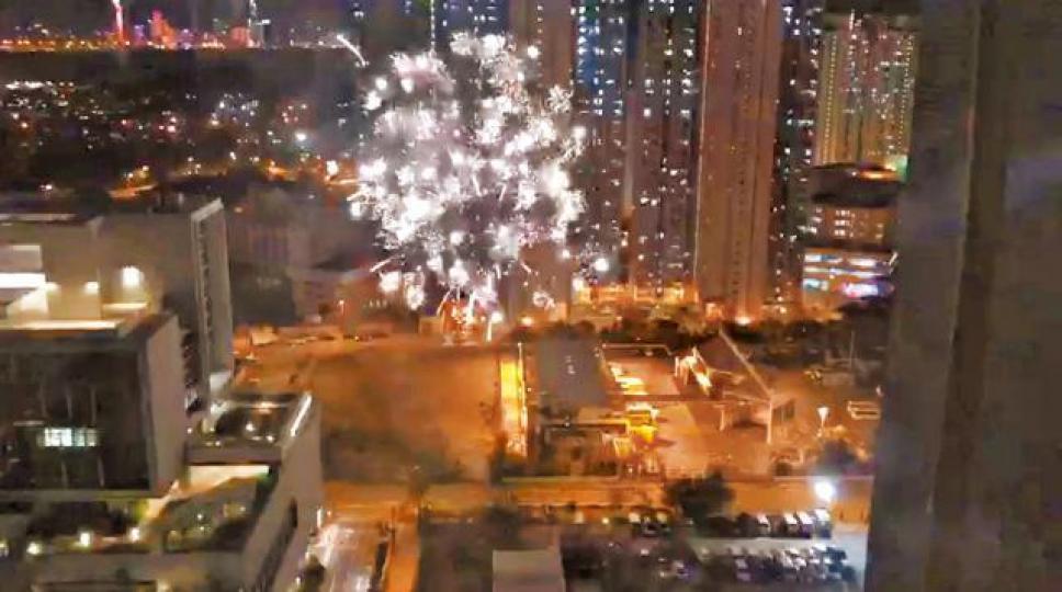 煙花爆發時照耀半空。警方展示撿獲的煙花紙箱。
