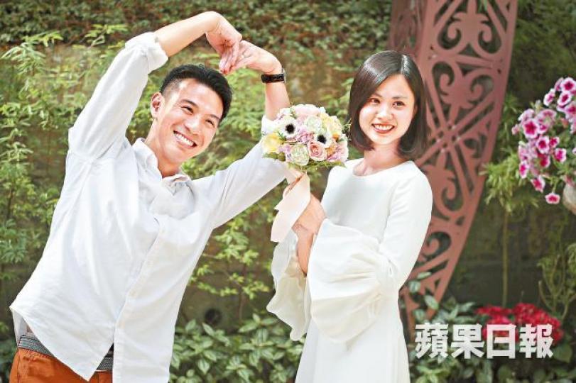 參加婚禮的情侶在佈景前拿着花球及擺出心形姿勢。何家達攝