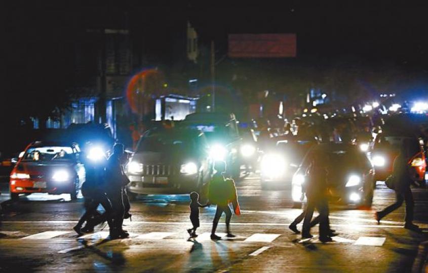 停電沒路燈下,卡拉卡斯市民摸黑在車頭燈光中過馬路。 美聯社 停電沒路燈下,卡拉卡斯市民摸黑在車頭燈光中過馬路。 美聯社