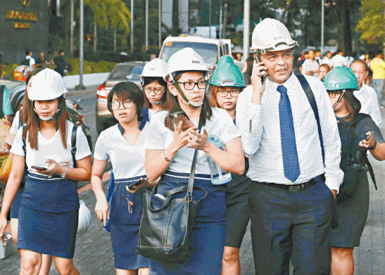 地震後馬尼拉大批辦公室職員戴頭盔走到街上。美聯社