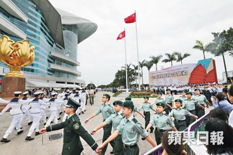 多個制服團體昨日在五四升旗禮用中式步操讓嘉賓檢閱。李家皓攝特首林鄭月娥及中聯辦主任王志民出席升旗禮；旁為主辦單位搞手霍啟剛。出席升旗禮的學生手持國旗及區旗，不斷揮舞「造勢」。