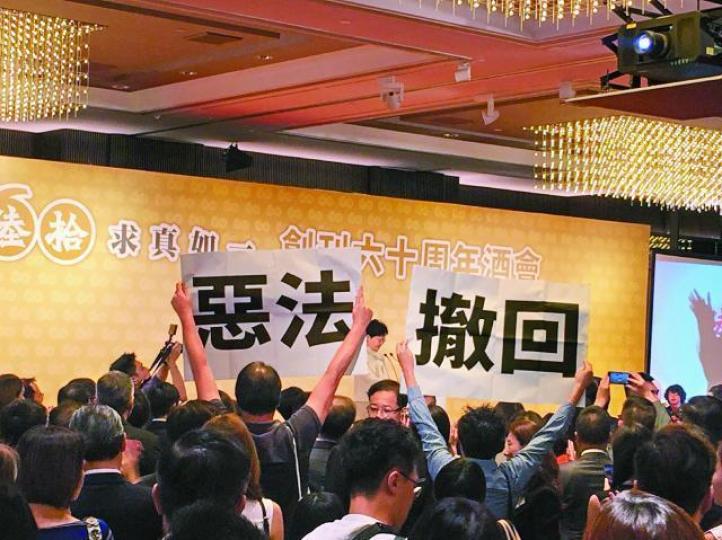 林鄭月娥昨晚出席《明報》創刊60周年酒會致辭，行為藝術家程展緯和黃宇軒全程向她高舉寫上「撤回」、「惡法」的示威牌。保安局長李家超